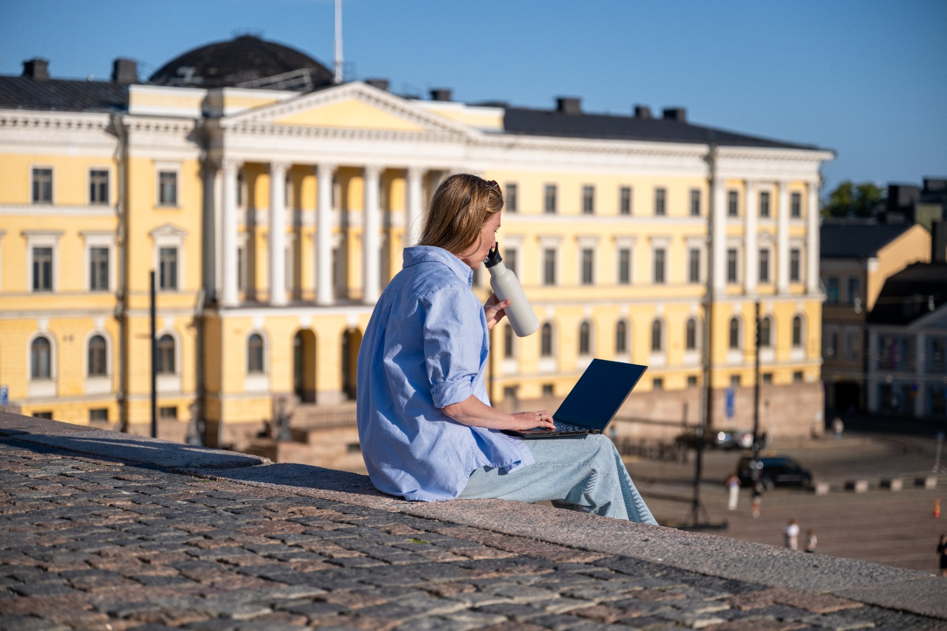 Junge Frau mit Laptop auf den Stufen des Senatsplatzes in Helsinki